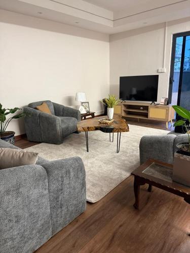 a living room with two couches and a flat screen tv at Villa Clair de Lagon in Blue Bay