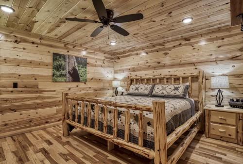 a log cabin bedroom with a bed and a ceiling fan at Cozy Log Cabin, hot tub, pool table, pool access in Gatlinburg