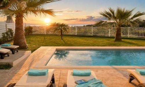 a swimming pool in a backyard with palm trees at Sunlight Villas Heated Pool in Mathés