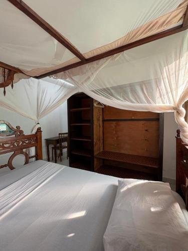 a bedroom with a white bed with a canopy at Villa Tuffah in Watamu