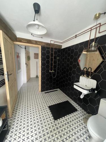 a bathroom with a toilet and a black and white tile floor at Winnica Bursztynowa in Możdżanowo
