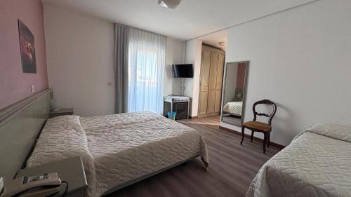 pokój hotelowy z dwoma łóżkami i krzesłem w obiekcie Hotel Splendor w Grado