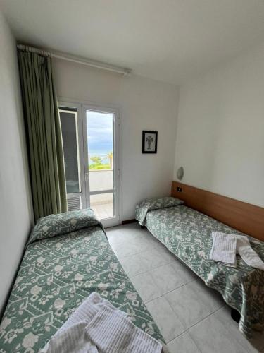 two beds in a room with a window at Hotel Il Timone in Specchiolla