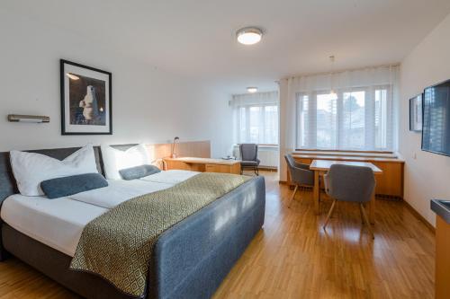 a bedroom with a bed and a desk and a table at Studiowohnungen am Rieger-Hof in Hartmannsdorf
