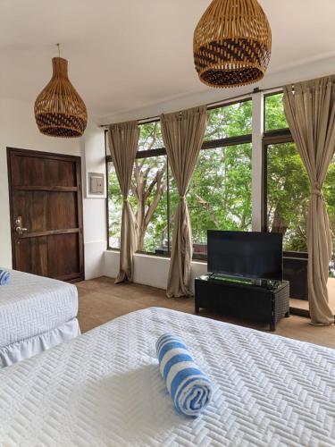 a bedroom with a white bed and large windows at Casa Bambú Hotel in Masaya