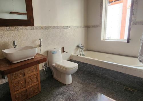 a bathroom with a toilet and a sink and a tub at Beach villa South Goa in Arossim-Cansaulim