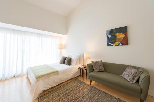 a bedroom with a bed and a couch next to a window at Bright Downtown Apartment in Porto