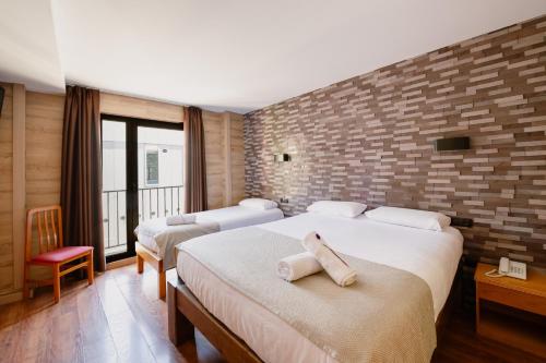 a bedroom with two beds and a brick wall at Cal Ruiz in Pas de la Casa
