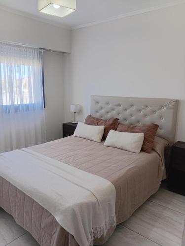 a white bedroom with a large bed with a large headboard at Ayres Apart in Chivilcoy