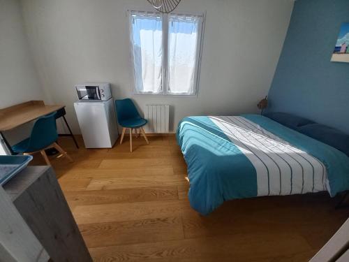 a bedroom with a bed and two blue chairs at Échappée iodée et nature à l'Île d'Oléron in Saint-Georges-dʼOléron