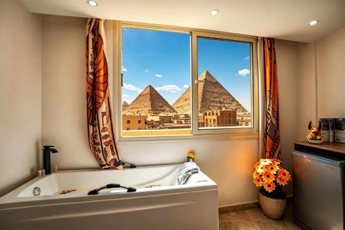 a bathroom with a view of the pyramids from a window at Tropitel Pyramids View Hotel in Cairo