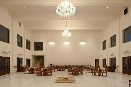 a large room with tables and chairs and a chandelier at Hari Bagh Jawai in Bijāpur