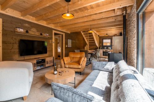 a living room with a couch and a tv at "Les Reflets de la Moselotte" - Chalet premium, calme & confort, vue Montagne, proche Centre et Pistes, Parking in La Bresse