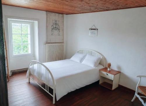a bedroom with a white bed and a table at Maison proche château in Bressuire