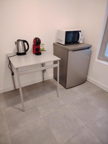 a kitchen with a table with a microwave and a table with a microwave at studio neuf in Beaumont-sur-Oise