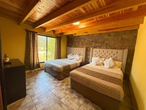 a bedroom with two beds and a stone wall at Lujo Rustico Lago Cerca Terraza Mascotas in Llano Grande