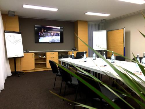 a conference room with a long table and a projection screen at Hotel Sonneck in Schwäbisch Hall