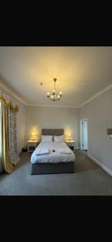 a bedroom with a bed and two tables and a chandelier at Edinburgh West Residences in Edinburgh