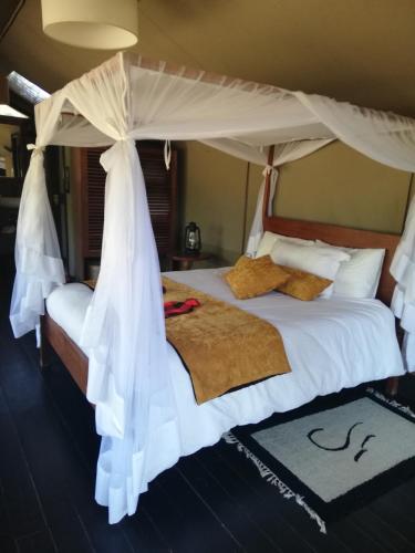 a bedroom with a white bed with a canopy at Eco mara forest camp in Ololaimutiek