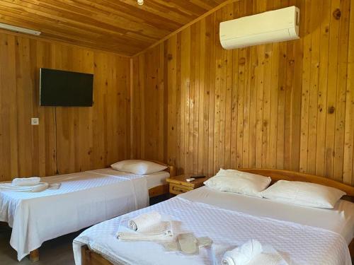 two beds in a room with wooden walls at Magic Camp&Bungalow in Fethiye