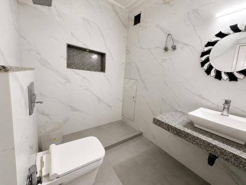 a white bathroom with a toilet and a sink at Hotel Swisston Palace in New Delhi