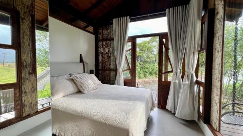 a bedroom with a bed and a large window at Cabana Flamboyant in Praia Grande