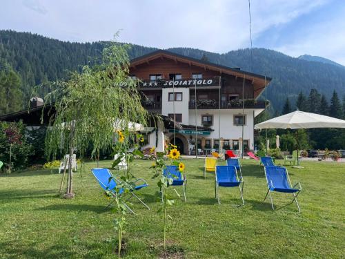 a group of chairs in a field in front of a building at Albergo Scoiattolo Dolomites Experience in Falcade