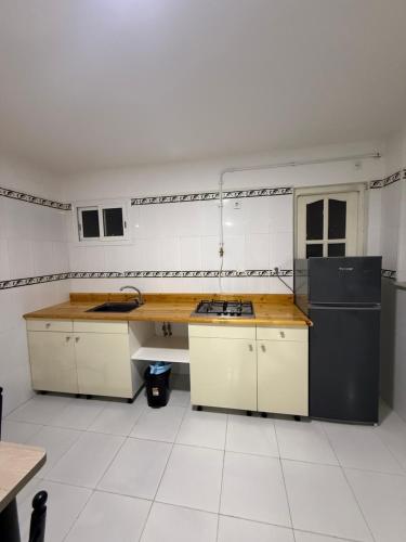 a large kitchen with white tile walls and counters at Résidence assia in Jijel