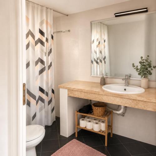 a bathroom with a sink and a toilet and a mirror at Among the pines in Katakolo