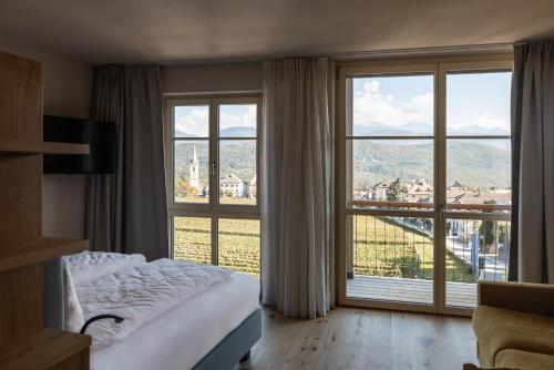 a hotel room with a bed and a large window at Essa Rooms NEW in Caldaro
