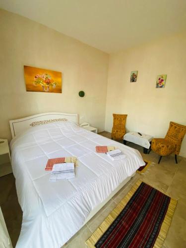 a large white bed in a room with two chairs at La Bohème - Chambres d'hôtes in Midoun