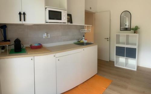 a kitchen with white cabinets and a microwave at Ciao Tavira in Tavira
