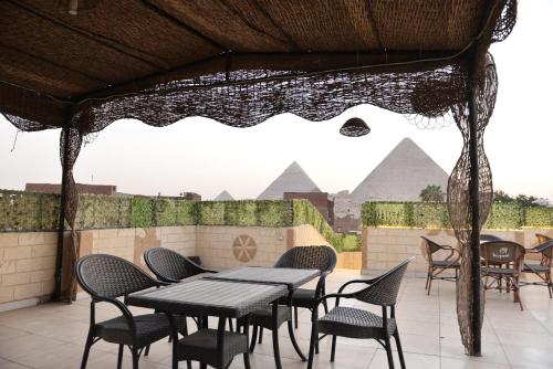 a patio with tables and chairs with pyramids in the background at Hur palace pyramids view in Cairo