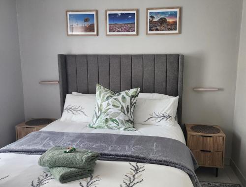 a bedroom with a bed with a gray headboard and pillows at Ocean Whisper Strandfontein in Strandfontein