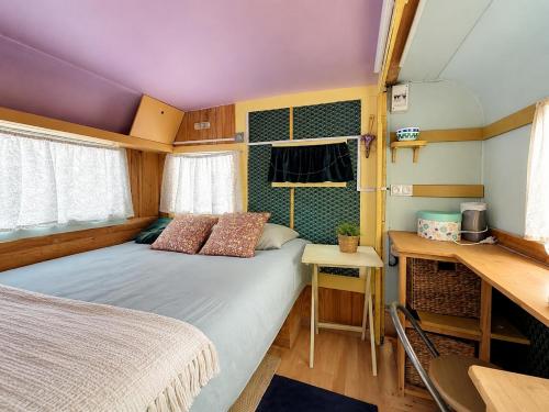 a small bedroom with a bed and a table and a desk at La Tiny de Lili in Draveil