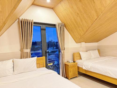 two beds in a room with a window at Dalat Mist House - Đà Lạt in Da Lat