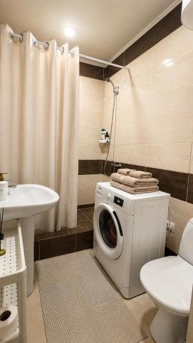 a washing machine in a bathroom with a toilet and a sink at Студия Назарбаева 57 in Kokshetau