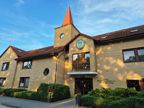 a large brick building with a clock tower on it at Uroczysko Porszewice - Ośrodek Rekolekcyjno-Konferencyjny koło Łodzi in Łódź