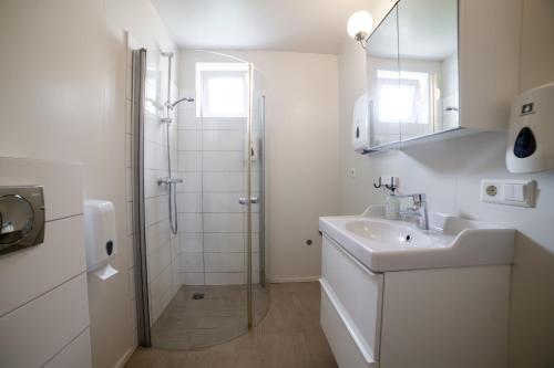a white bathroom with a shower and a sink at Hali Country Hotel in Gerdi