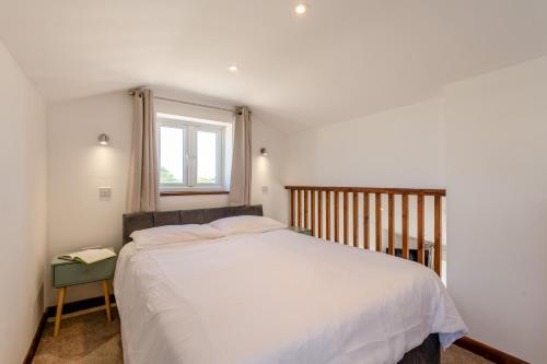 a bedroom with a large white bed and a window at Kent Coast Stays - Cottages in Birchington