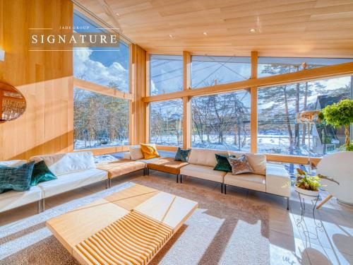 a living room with couches and a lot of windows at JADE Amber Resort Hakuba in Hakuba
