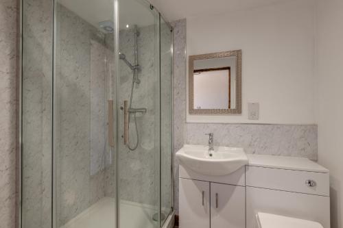 a bathroom with a glass shower and a sink at Kent Coast Stays - Cottages in Birchington