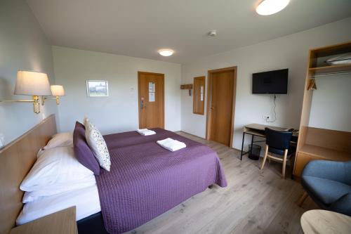 a hotel room with a purple bed and a desk at Hali Country Hotel in Gerdi