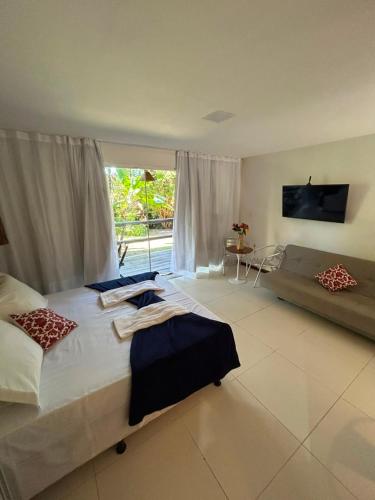 a large bedroom with a large bed and a couch at Bangalô Villas do Pratagy - Flor de Lótus B1 in Maceió