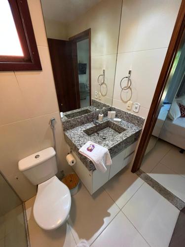 a bathroom with a toilet and a sink with a mirror at Bangalô Villas do Pratagy - Flor de Lótus B1 in Maceió
