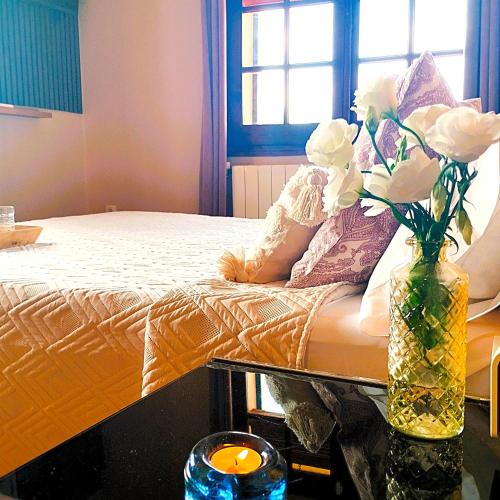 a vase filled with white flowers sitting next to a bed at La Masia Costa Brava -Adults Only in Garrigás