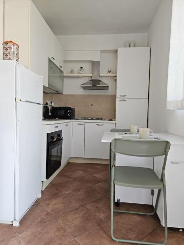 a white kitchen with a table and a refrigerator at La sosta di Strada in Strada