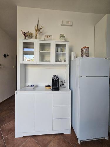 a kitchen with white cabinets and a white refrigerator at La sosta di Strada in Strada