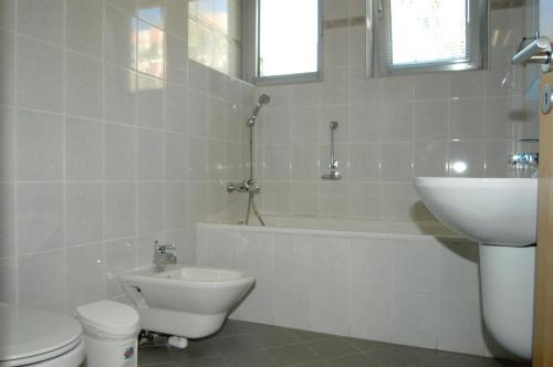 a bathroom with a toilet and a sink and a bath tub at Kék Hold Hotel in Marcali