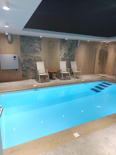 a large swimming pool with chairs and a table at Willa Górska Pasja in Szczyrk